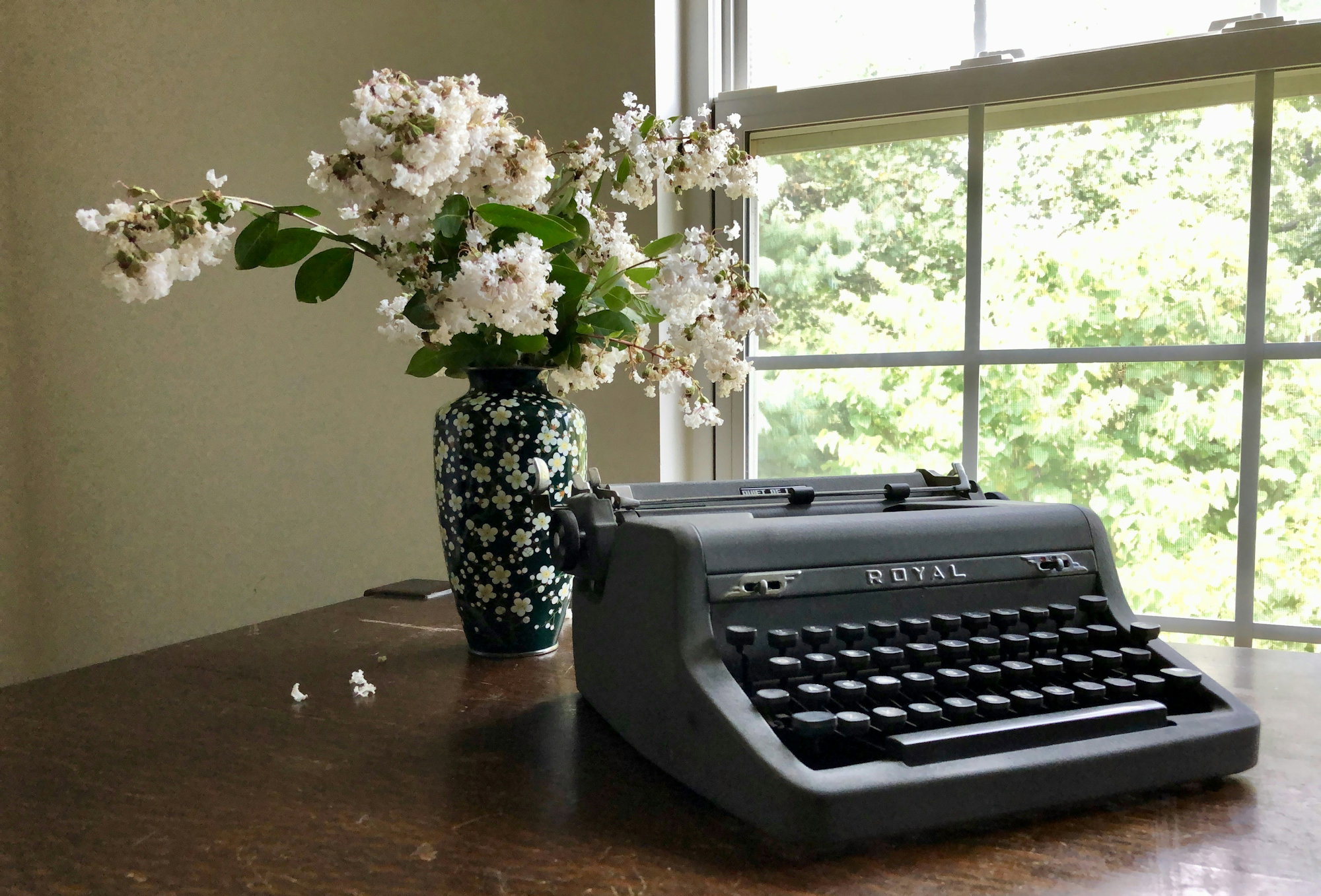 gray-royal-typewriter-near-white-flowers-in-vase-on-brown-table.jpg gray Royal typewriter near white flowers in vase on brown table